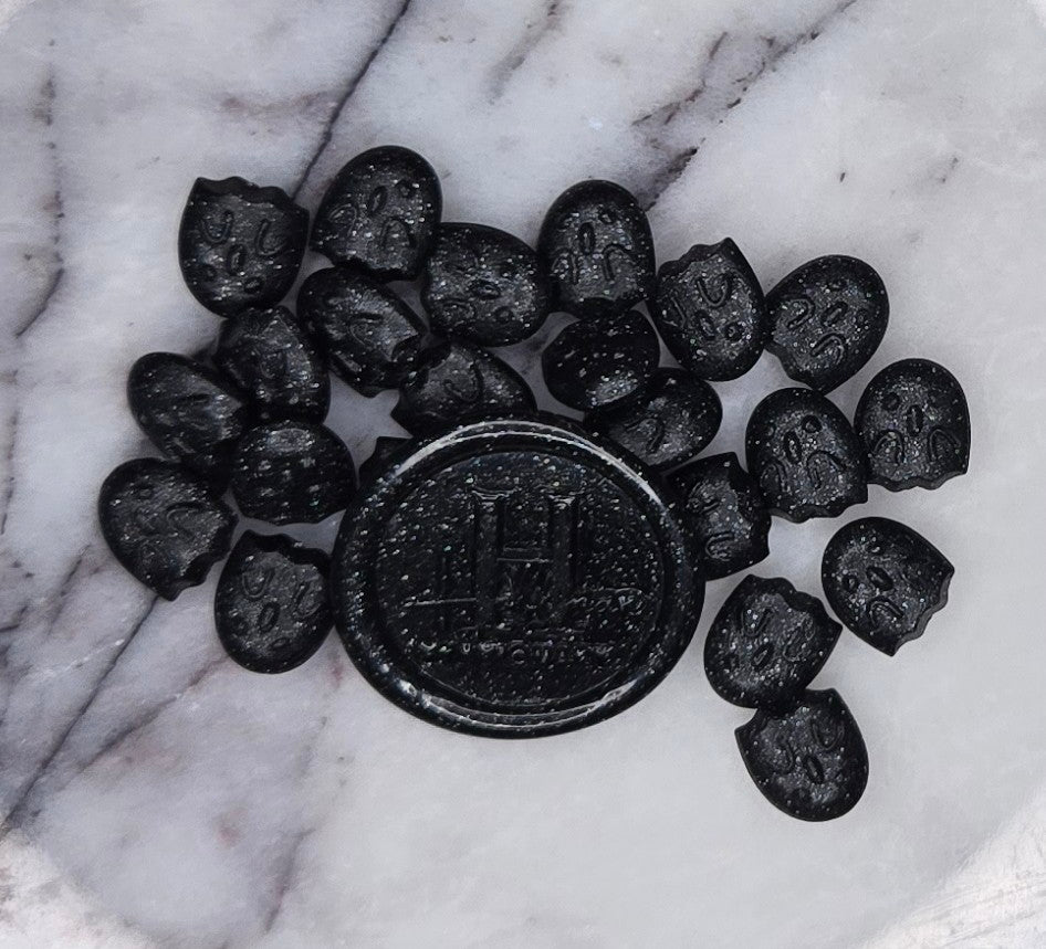 deep, cosmic black wax seal bead flecked with glittering specks that shimmer like distant stars in the void