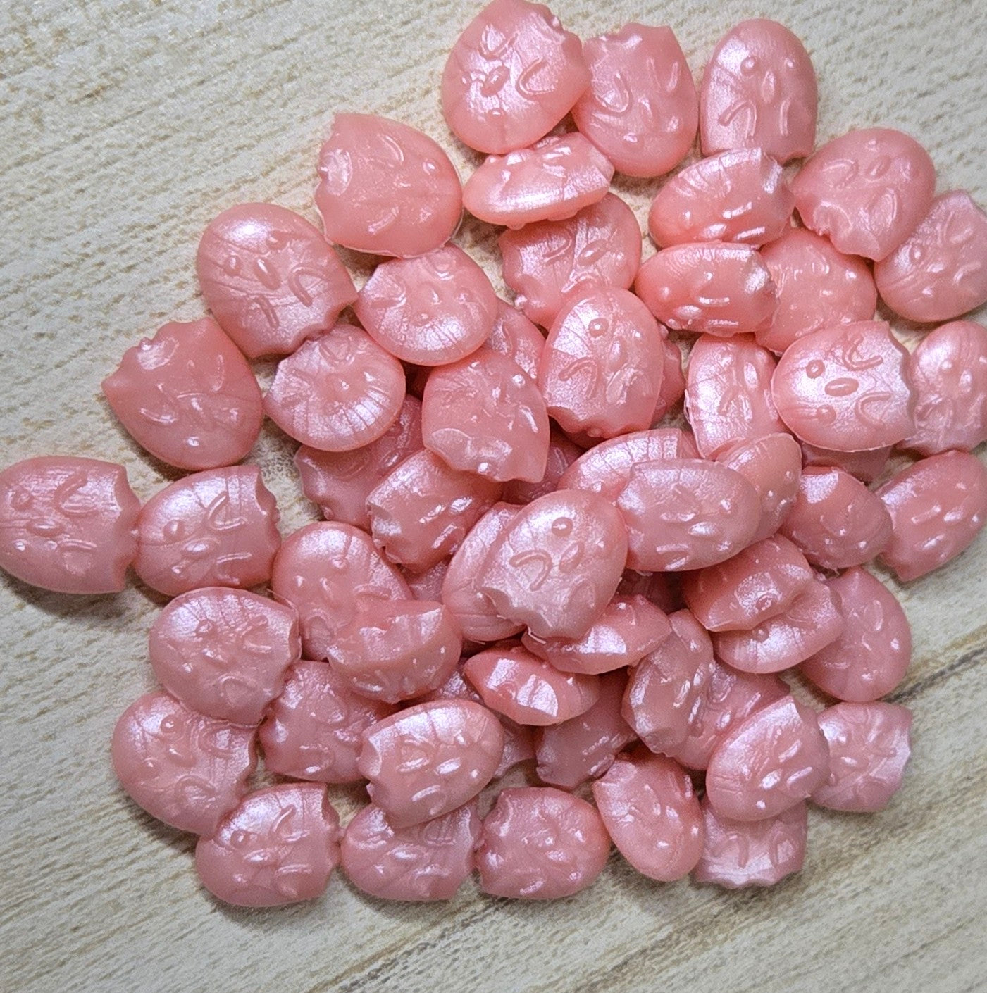 a delicate, shimmering wax seal bead in soft peach tones that glows with a gentle, iridescent luster like spring petals kissed by morning light